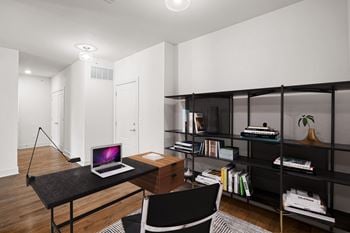 A black desk with a laptop on it in a room.